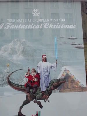 Awesome ad seen in a shop window. Santa, a dinosaur, and a lightsaber wielding Jesus? Sure, why not!